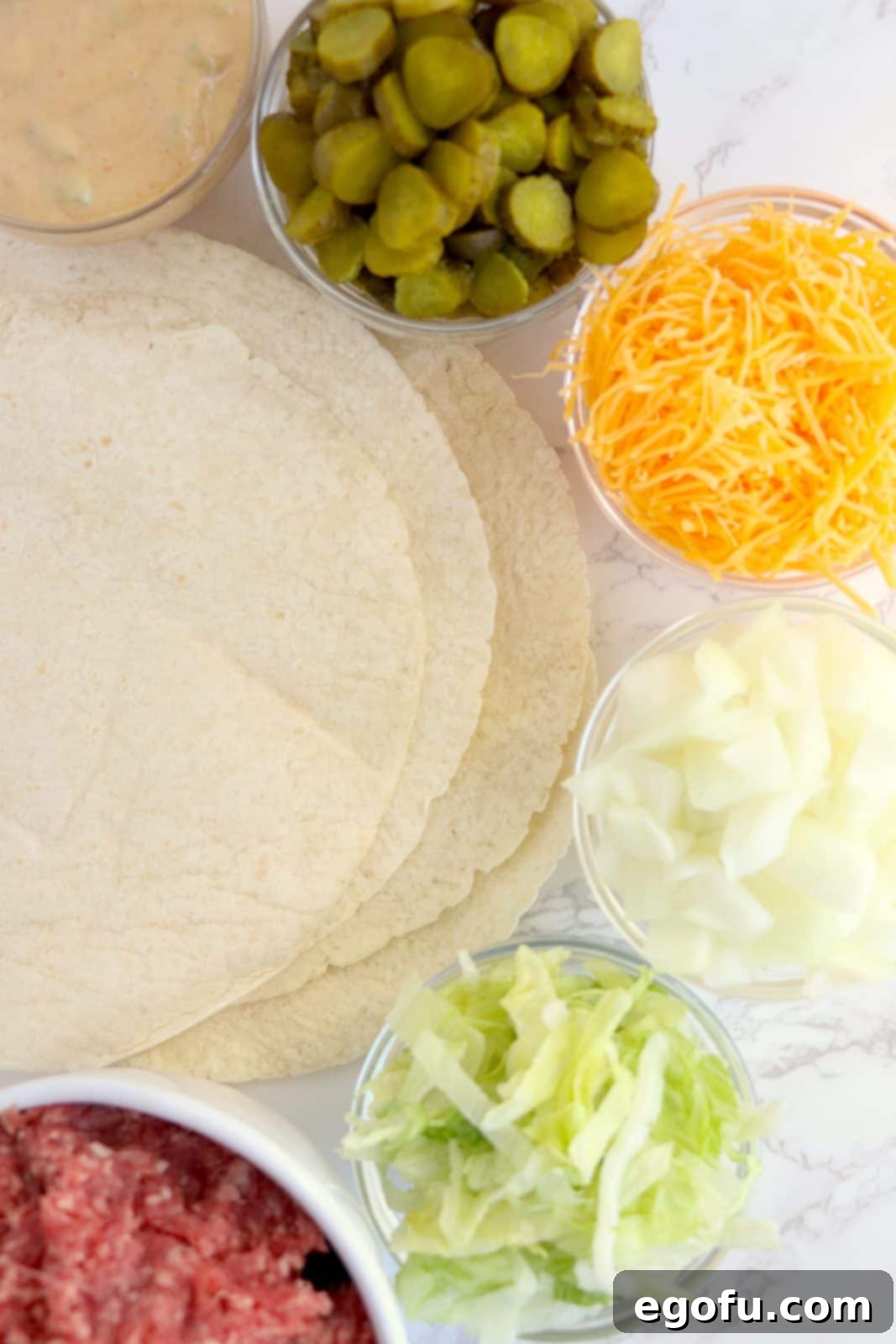 Ingredients needed: mayonnaise, diced dill pickles, mustard, ketchup, smoked paprika, onion, ground beef, tortillas, lettuce and cheddar cheese.