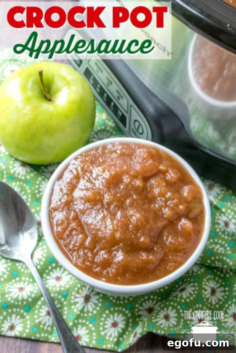 Easy homemade Crock Pot Applesauce in a small white bowl, with a fresh green apple in the background.