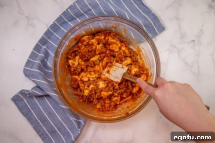 Puffy Pizza Bake 11 Italian sausage, biscuits and pizza sauce stirred together in a bowl.