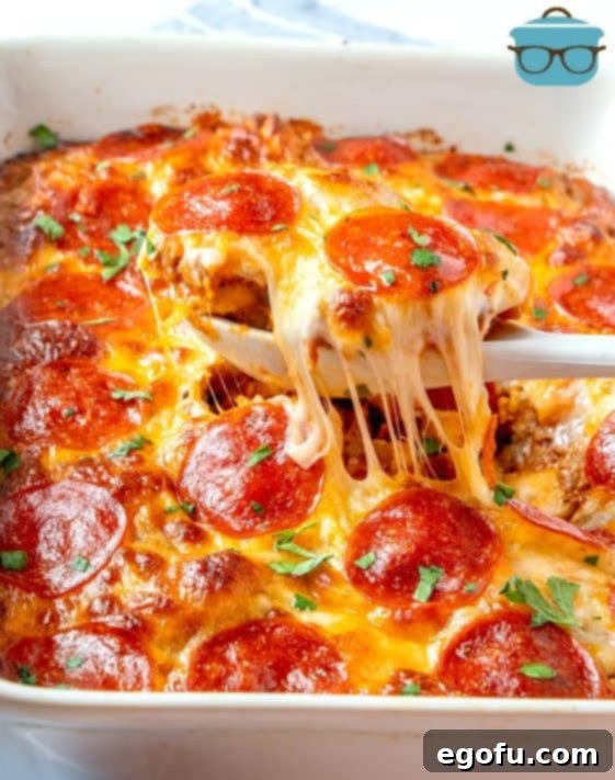 Puffy Pizza Bake 14 Bubble Up Pizza, finished, in a baking dish with a spoon pulling out a serving with melted cheese