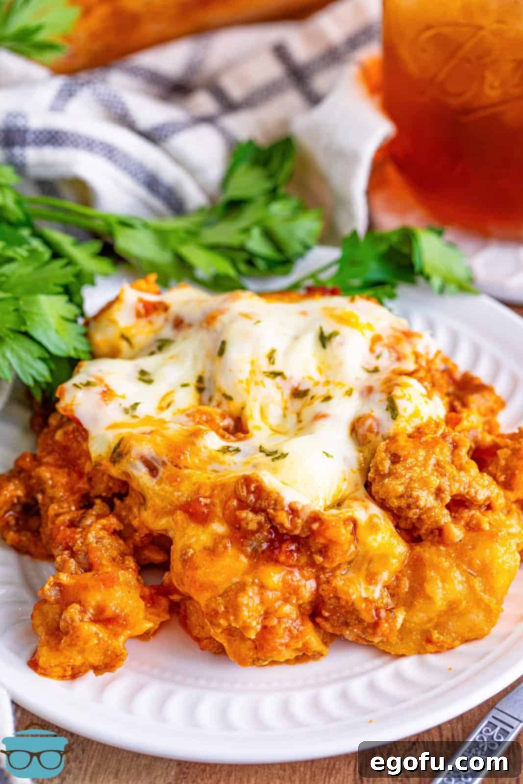 A generous serving of Bubble Up Lasagna on a white plate, showcasing delightful layers of biscuits, savory meat sauce, and melted, golden-brown cheese.