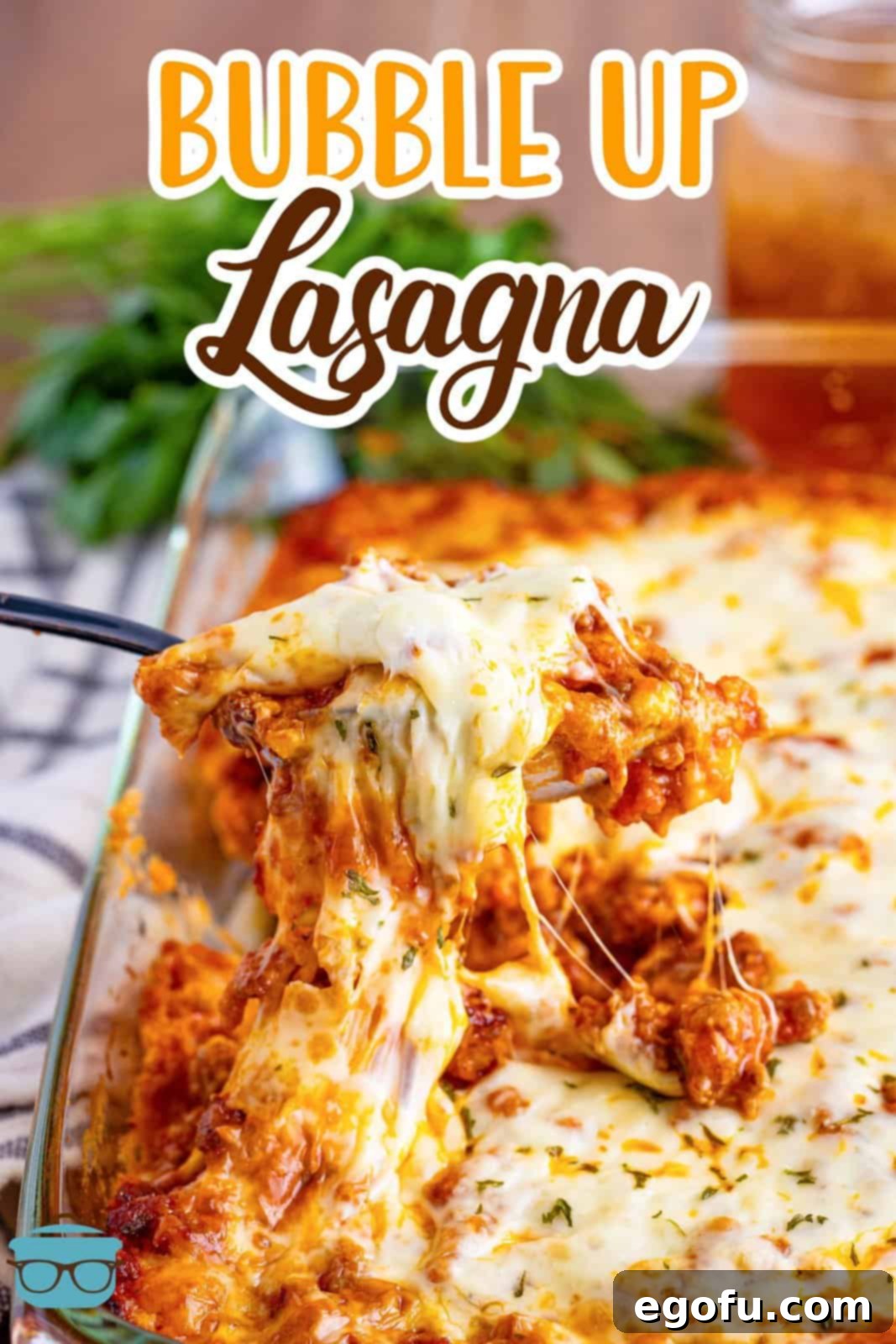 A serving spoon lifting a generous portion of cheesy, savory Bubble Up Lasagna from a glass baking dish, highlighting its comforting layers.