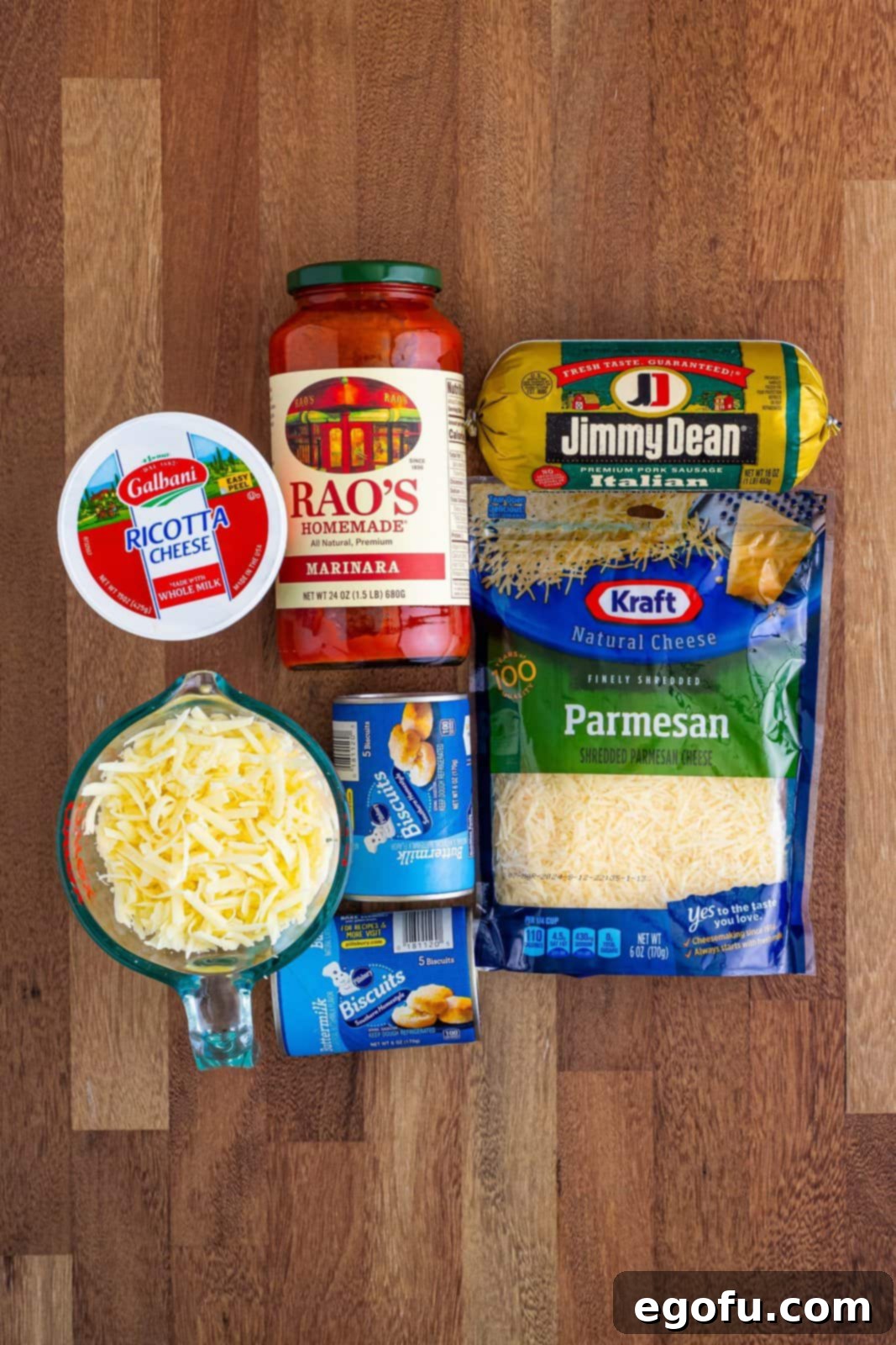A vibrant assortment of all the key ingredients required for Bubble Up Lasagna: fresh mozzarella cheese, rich marinara sauce, grated Parmesan cheese, versatile canned biscuit dough, creamy ricotta cheese, and savory Italian sausage.