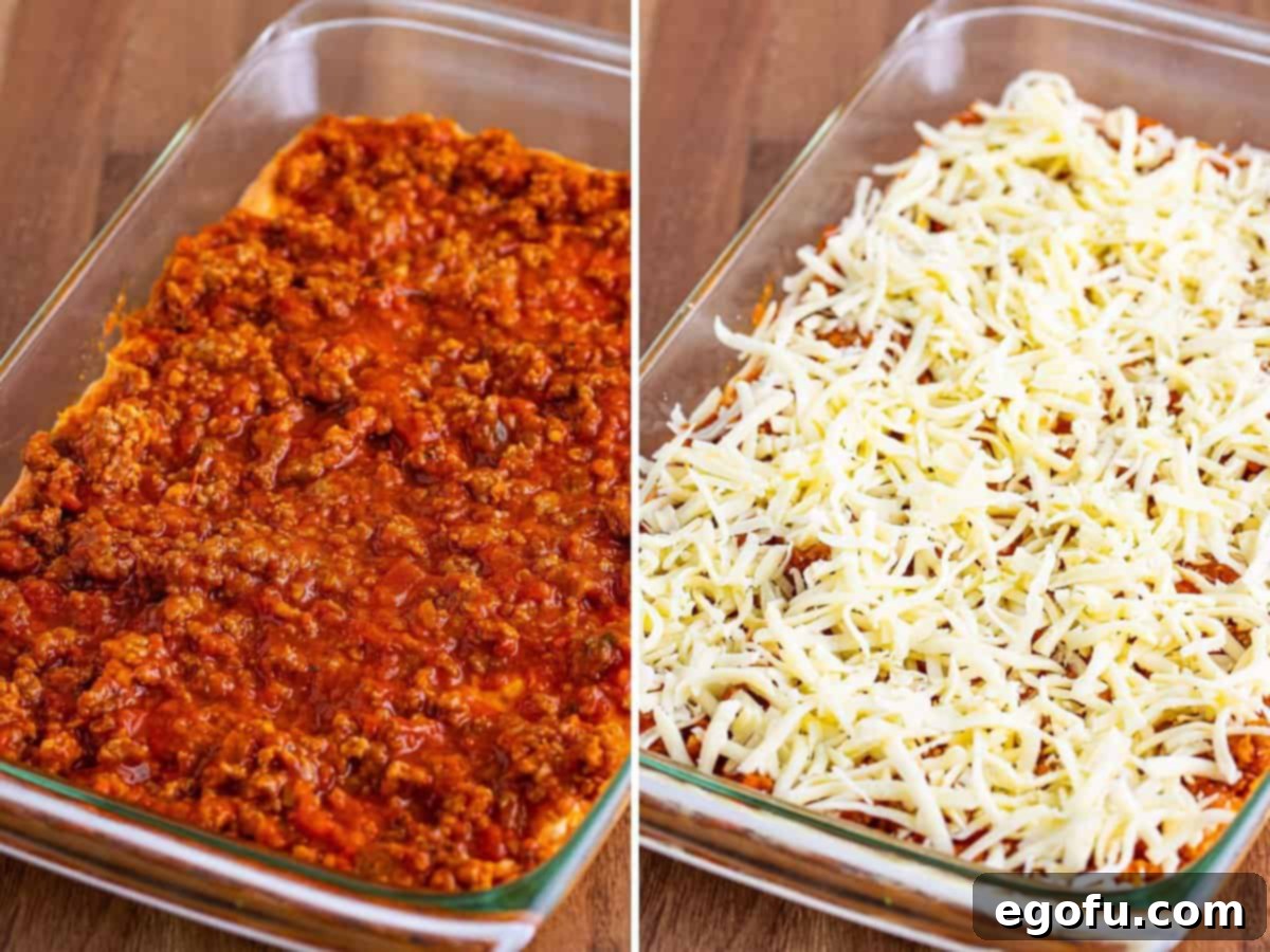 The baking dish is filled with distinct layers: a base of biscuit and cheese mixture, topped with the savory meat sauce, and finished with a generous sprinkle of mozzarella cheese, ready for baking.