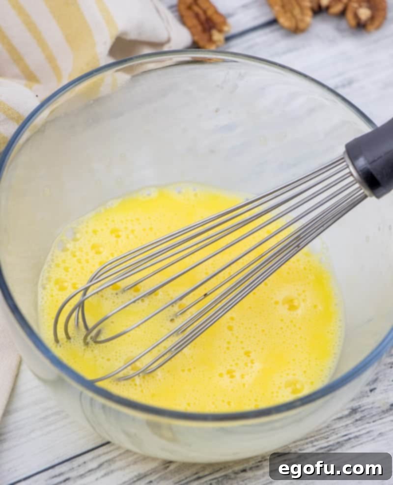 an egg being whisked in a clear bowl.