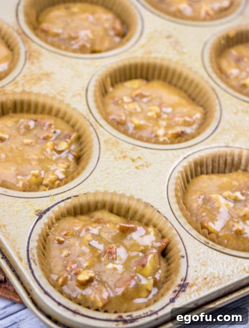 pecan pie muffin batter added to cupcake liners in a muffin tin.
