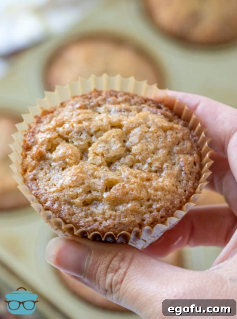 A hand holding a fully baked pecan pie muffin close up. 