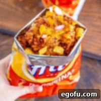 a bag of Fritos cut open with chili, cheese and diced onions on top.