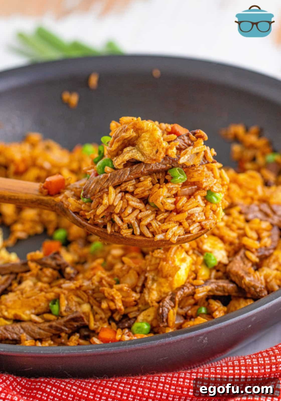 Sizzling Beef Fried Rice 11 Wooden spoon holding up some of the Beef Fried Rice out of pan.