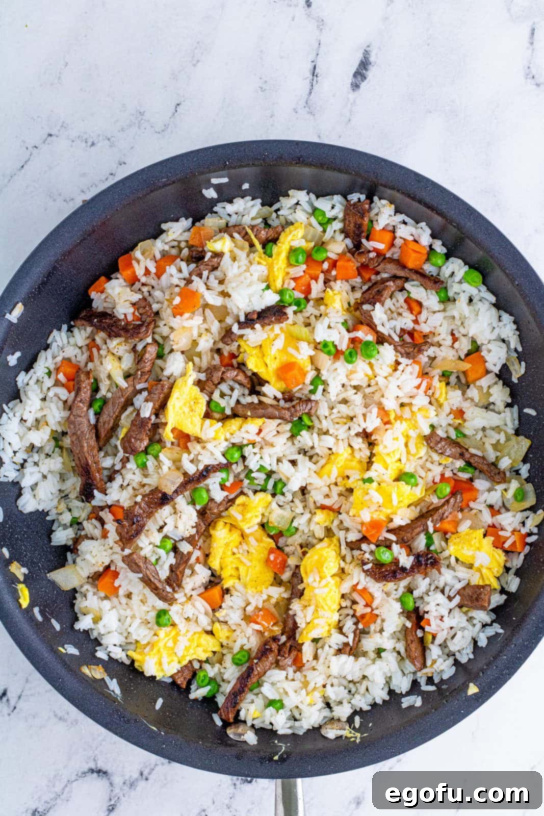 Sizzling Beef Fried Rice 9 Beef, vegetables and eggs stirred into rice in pan.