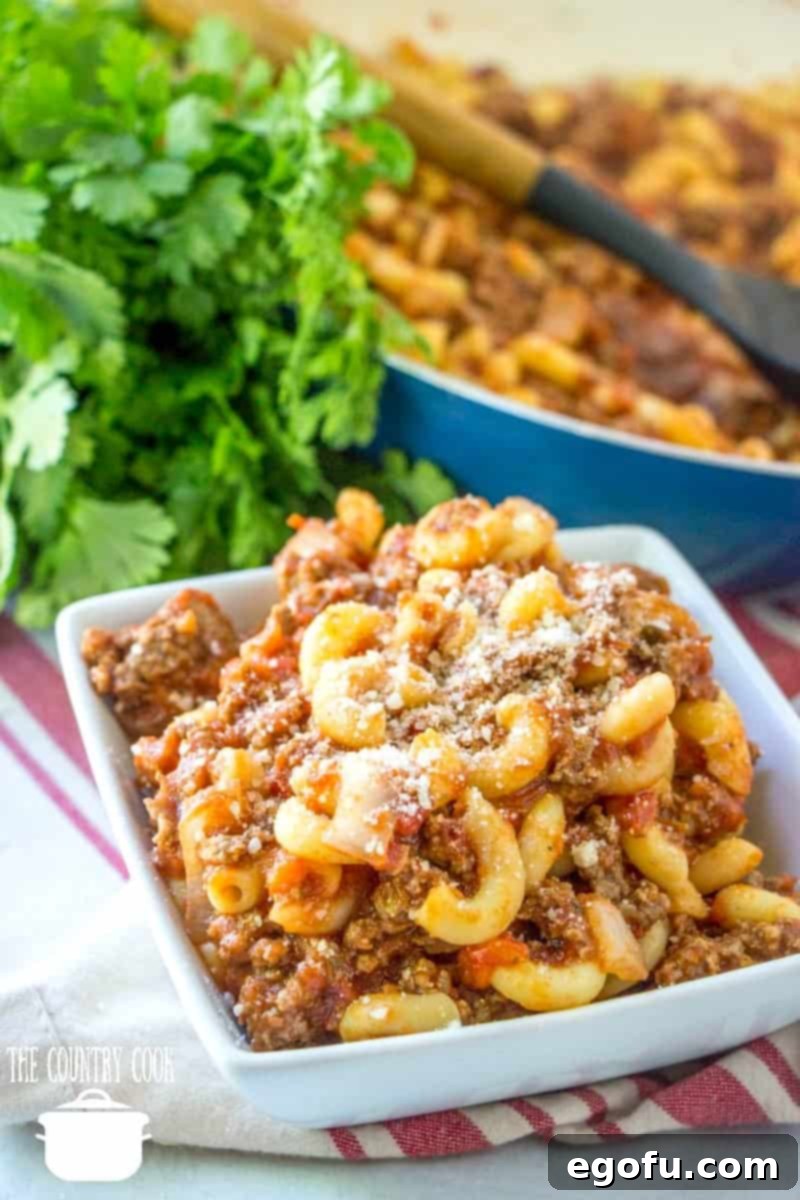 A white square dish filled with classic American Goulash, also known as Slumgullion or Johnny Marzetti, ready for a comforting meal.