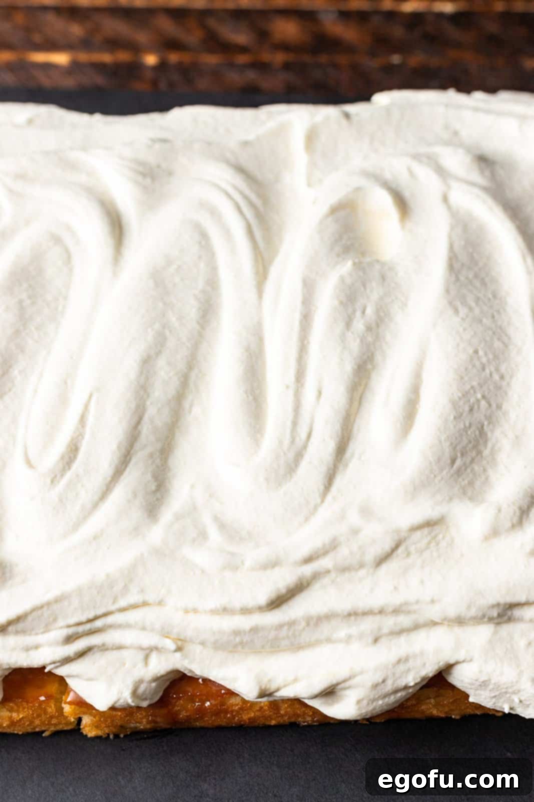 New Orleans Bananas Foster Poke Cake 9 The creamy Cool Whip and pudding topping beautifully spread over the banana layer of the cake, ready for the final garnish.