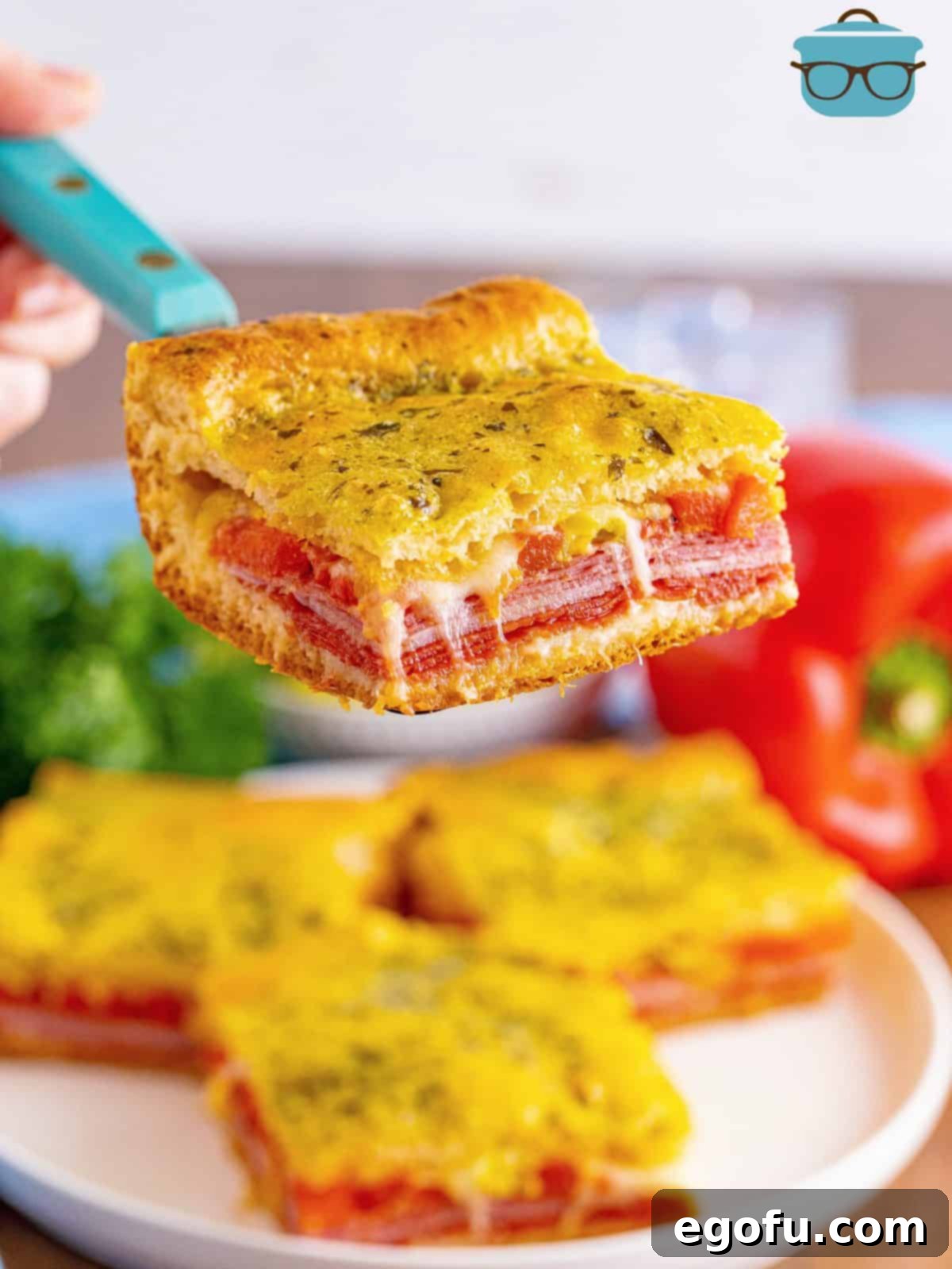 A spatula lifting a perfectly baked Italian Sub Square, showcasing its golden crust and savory filling.