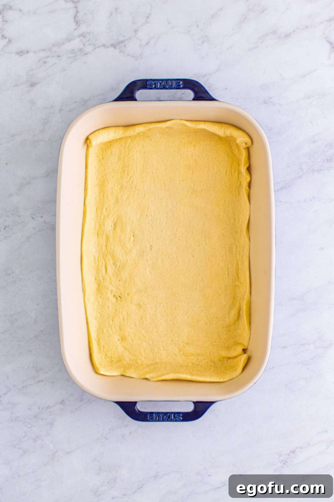 A crescent roll dough sheet perfectly pressed into the bottom of a 9x13 inch baking dish, forming the base for the Italian Sub Squares.