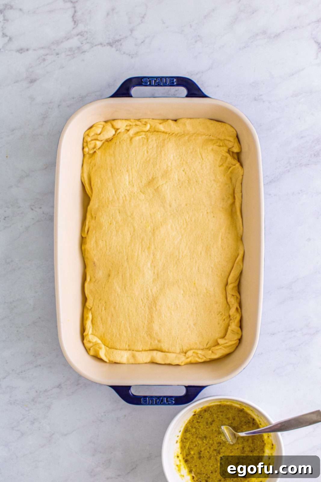 The top crescent dough sheet covering the delicious filling, with the seams pinched together to create a sealed package.