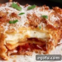 Close up square image with bite taken out of a piece of Deep Fried Lasagna showing center, emphasizing its gooey, cheesy filling and crispy exterior.