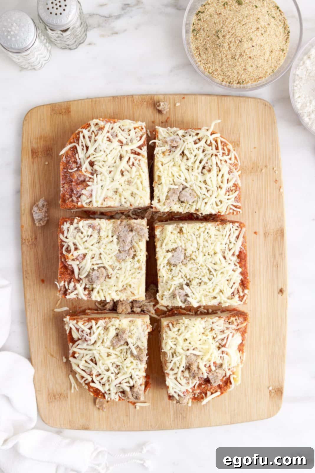 Frozen lasagna expertly cut into 6 evenly sized dinner portions arranged on a cutting board, ready for the next step.