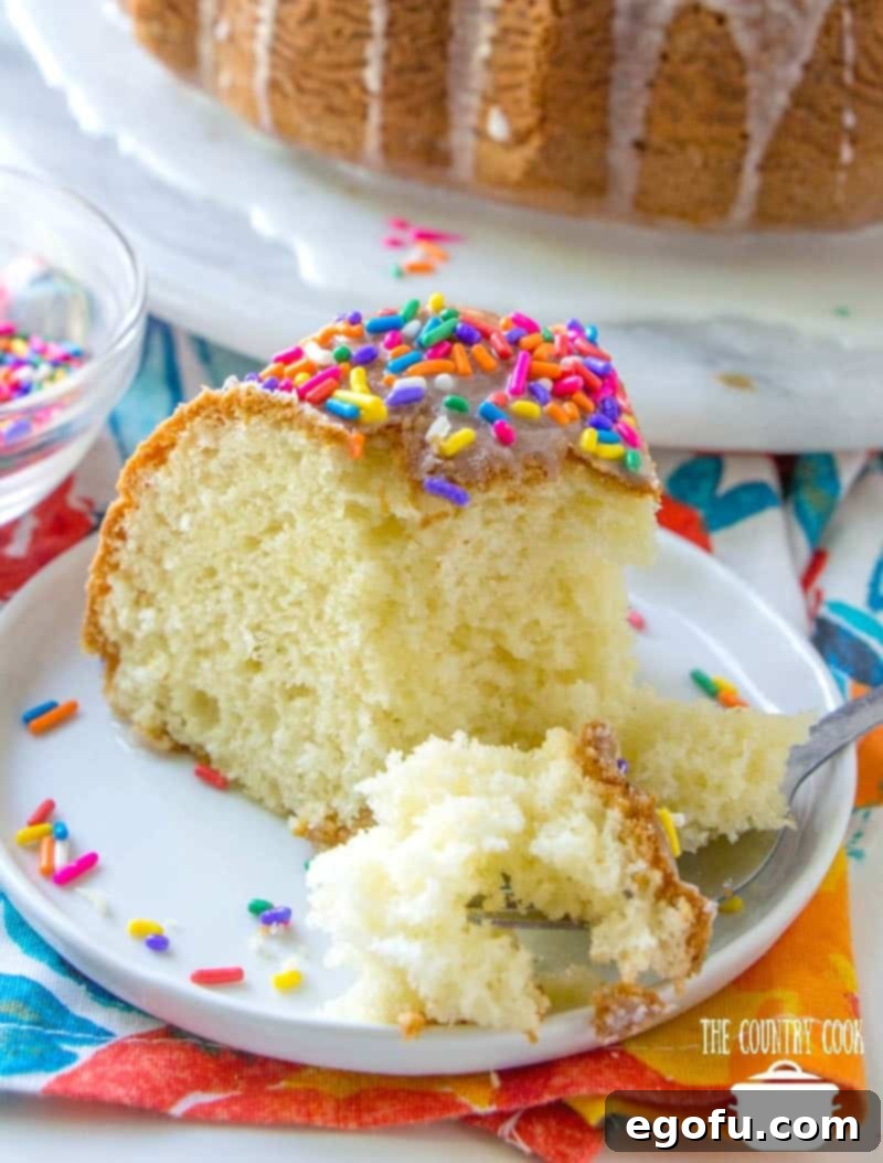 slice of bundt cake on a small round white plate with a fork removing a portion.