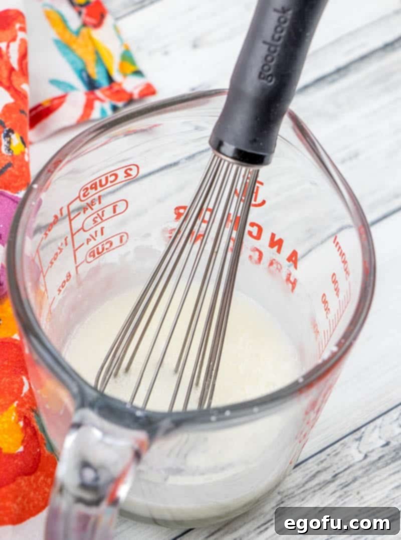powdered sugar and milk whisked together in a measuring cup.