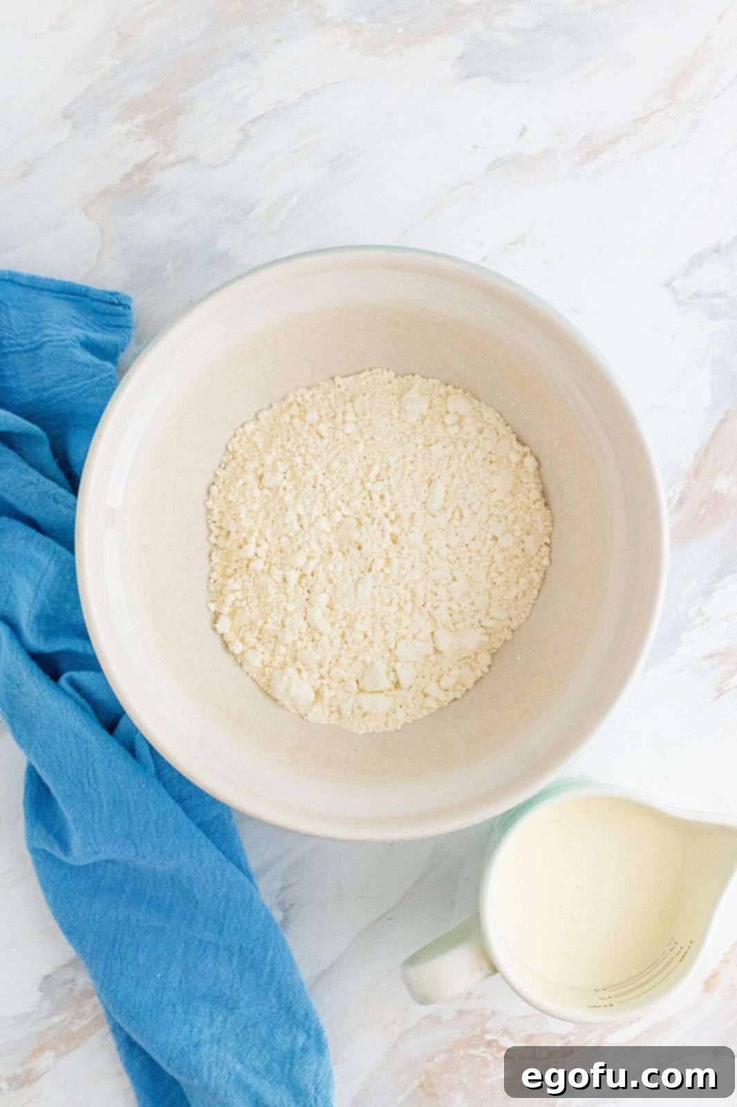 A white bowl filled with white, fluffy self-rising flour.