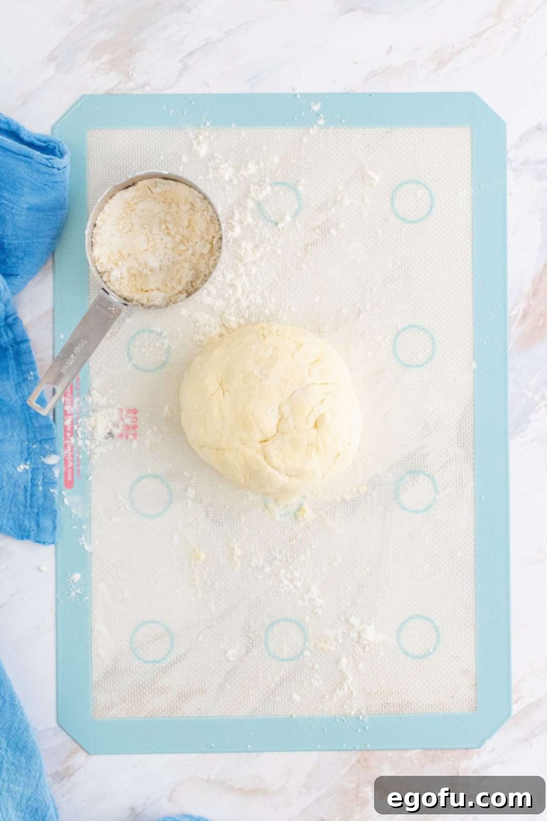 Cream biscuit dough placed from a bowl onto a lightly floured silicone baking mat.