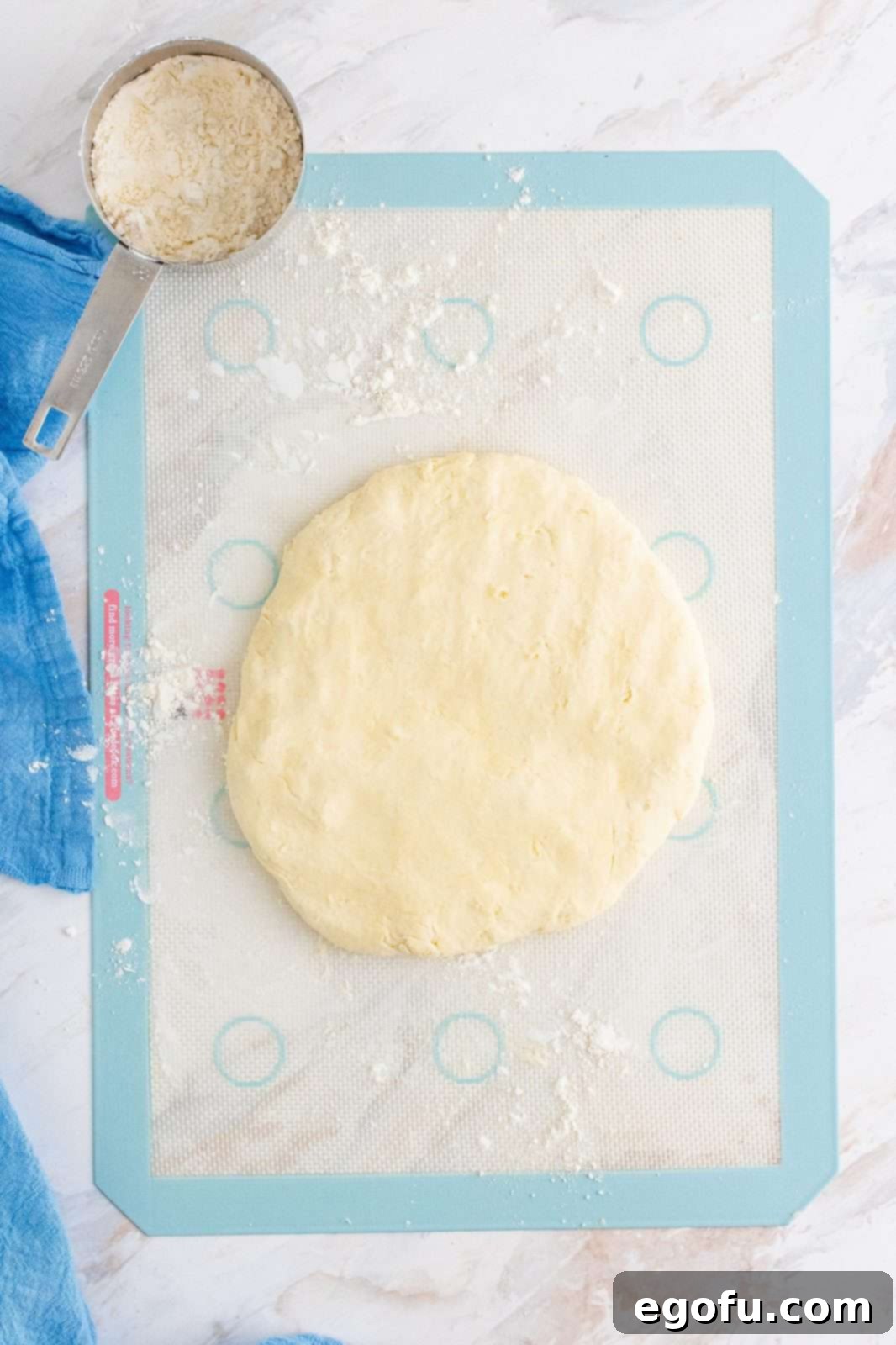 Biscuit dough gently spread into a large circular shape on a silicone baking mat.