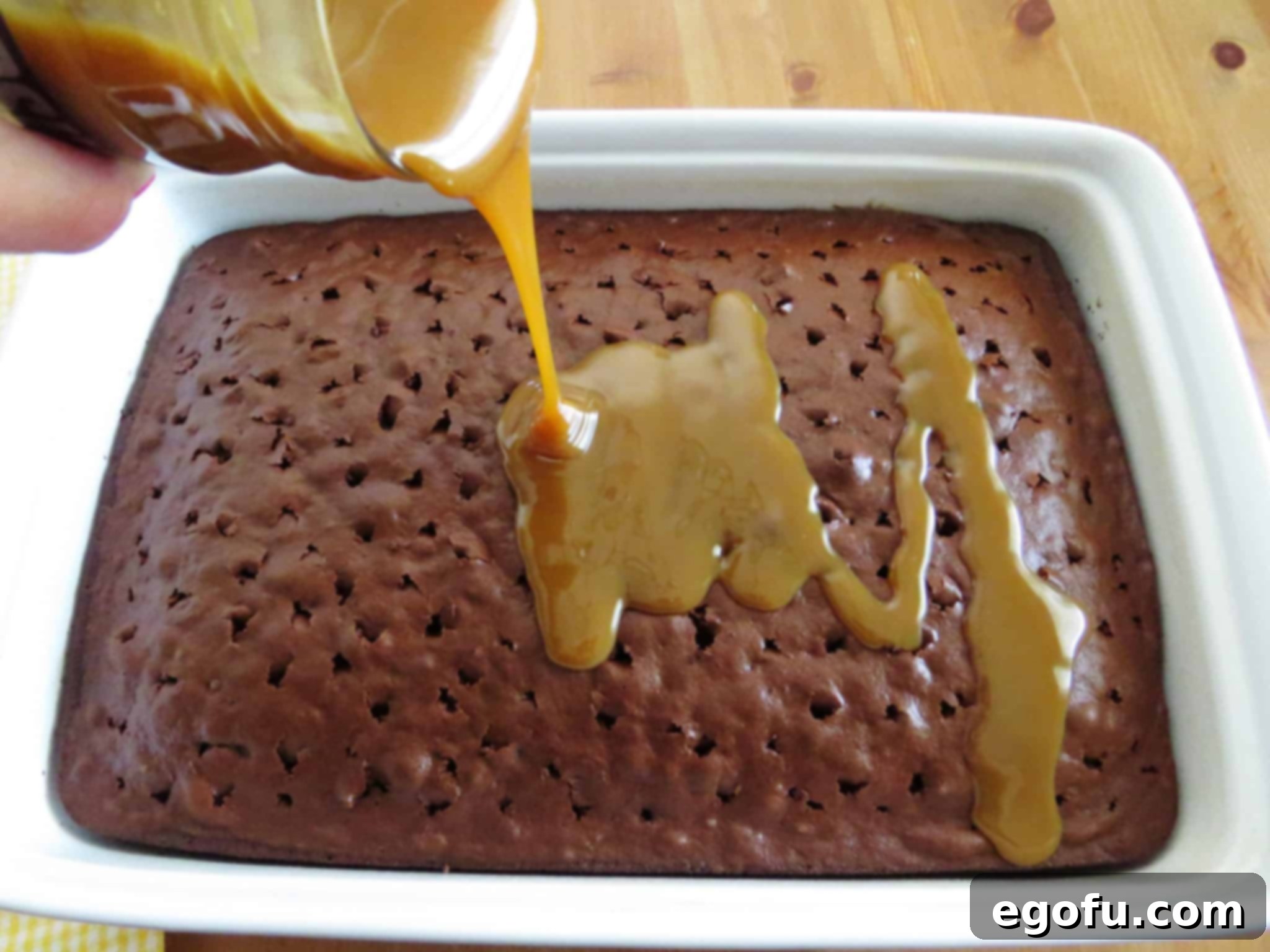pouring jarred caramel sauce over warm chocolate cake.