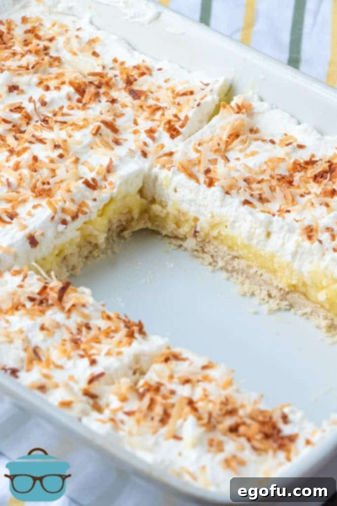 Fully finished Coconut Cream Pie Bars presented in the baking pan, with two slices already neatly cut and elegantly topped with golden toasted coconut, poised and ready for serving.