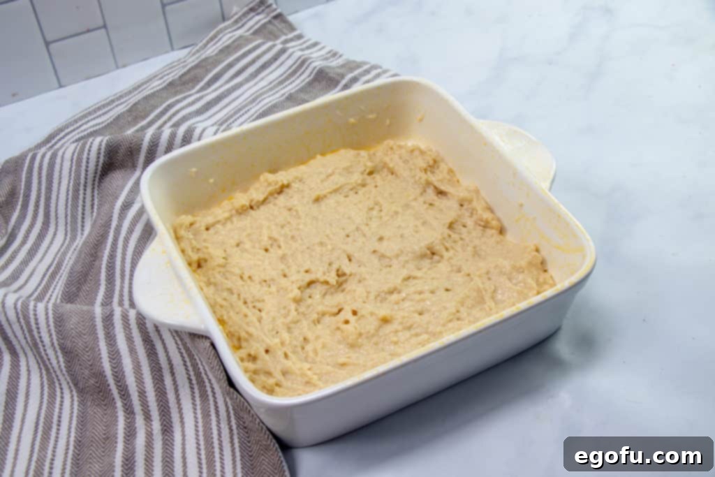 crumb cake batter spread into an white square baking dish.
