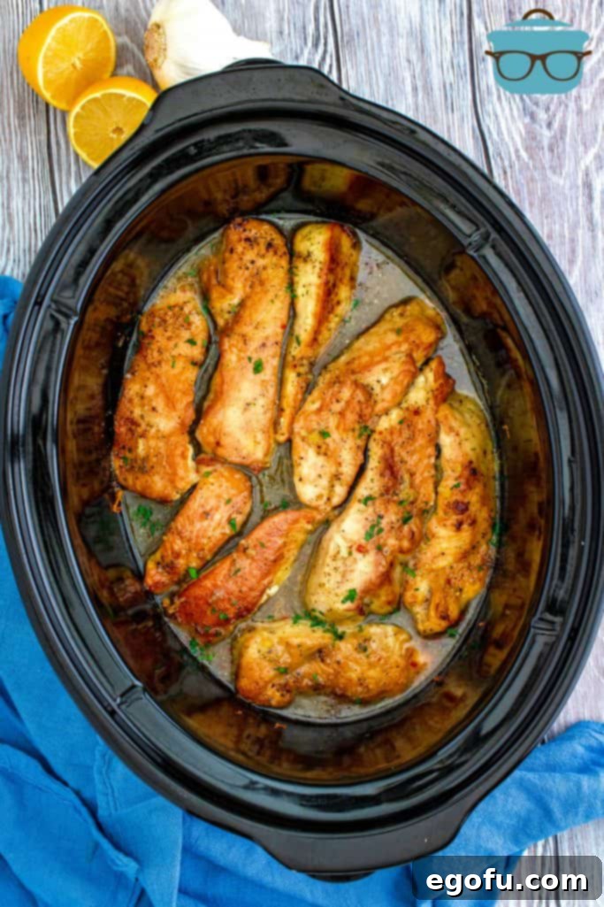 Zesty Slow Cooker Lemon Garlic Chicken 9 fully cooked lemon garlic chicken in an oval black slow cooker.