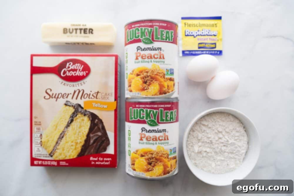 Arrangement of key ingredients: yellow cake mix, peach pie filling, active dry yeast, butter, and flour, laid out on a kitchen counter.