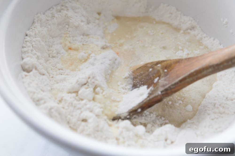 Close-up shot of yellow cake mix, flour, yeast, and warm water in mixing bowls, ready to be combined for the cake batter.