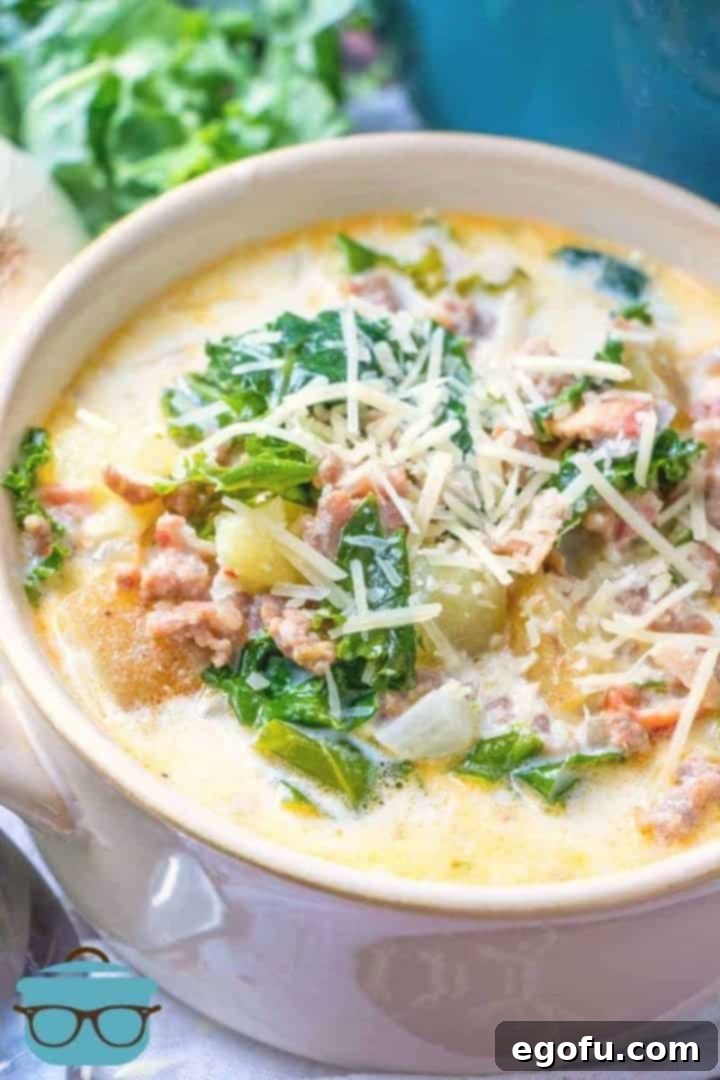 The Ultimate Copycat Olive Garden Zuppa Toscana Recipe 2 close up photo of a white bowl with a serving of Zuppa Toscana topped with shredded Parmesan cheese.