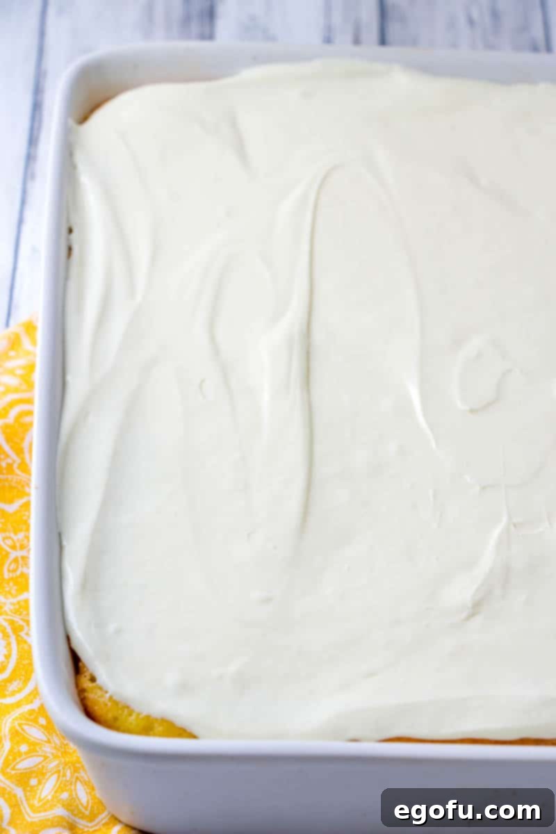 Zesty Lemon Drop Bliss 11 The fully frosted Lemon Drop Cake, adorned with a smooth and appealing layer of whipped lemon frosting, ready to be chilled.