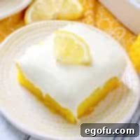 Zesty Lemon Drop Bliss 13 Lemon Drop Cake recipe with a slice removed, showing layers of cake, glaze, and frosting.