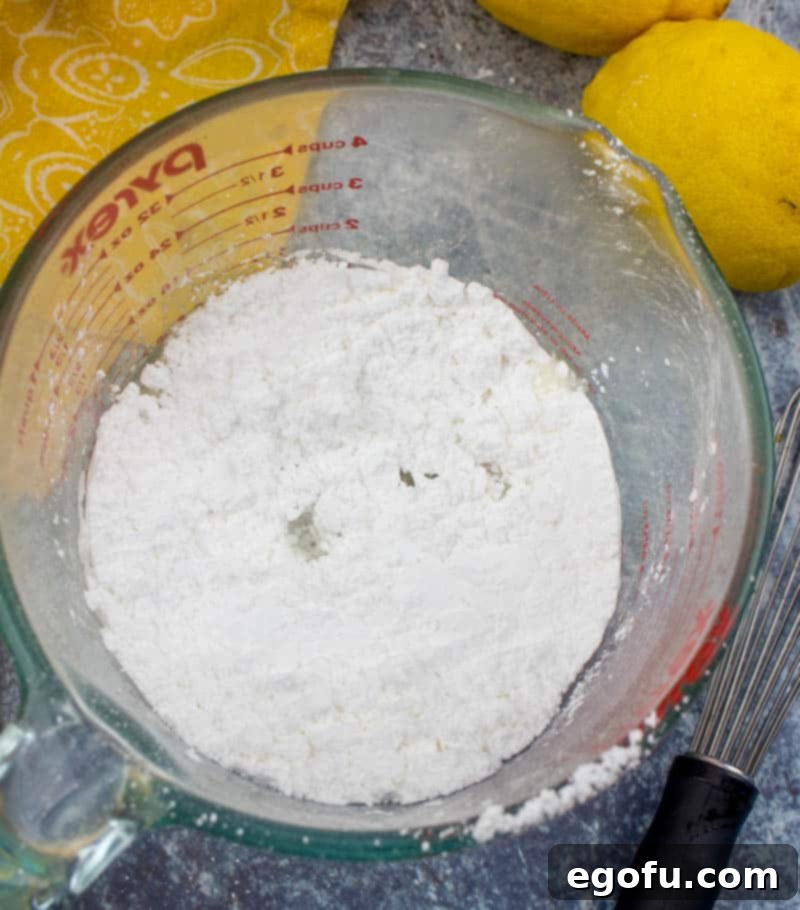 Zesty Lemon Drop Bliss 7 Powdered sugar and fresh lemon juice being whisked together in a bowl, forming a smooth and luminous lemon glaze.
