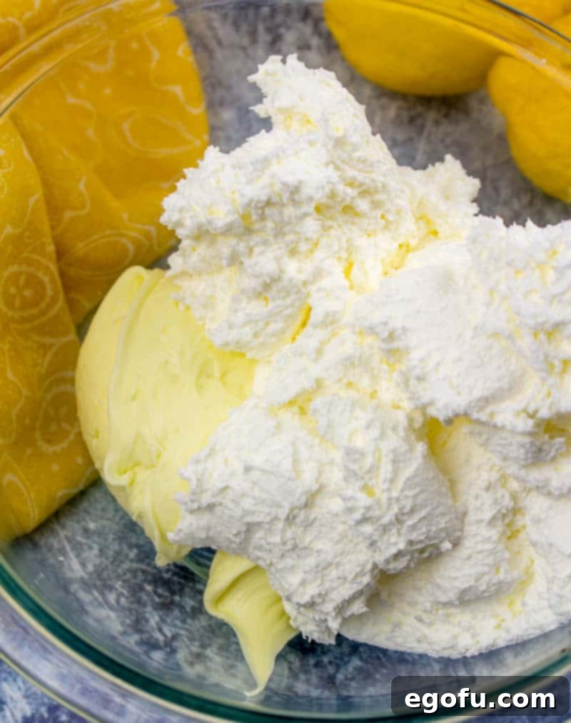 Zesty Lemon Drop Bliss 10 Lemon frosting and Cool Whip (whipped topping) being combined in a bowl to create a light, airy, and fluffy whipped frosting.