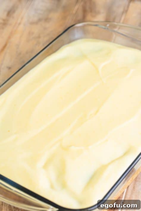 Super Moist Carrot Poke Cake 14 Cheesecake pudding spread over a carrot cake with holes.