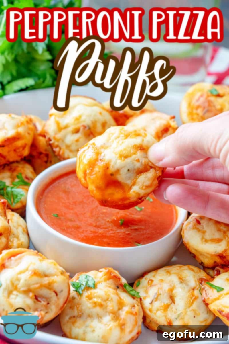 Cheesy Pepperoni Poppers 3 Pepperoni Pizza Puffs recipe from The Country Cook, hand holding one puff and dipping it into a bowl of marinara sauce.