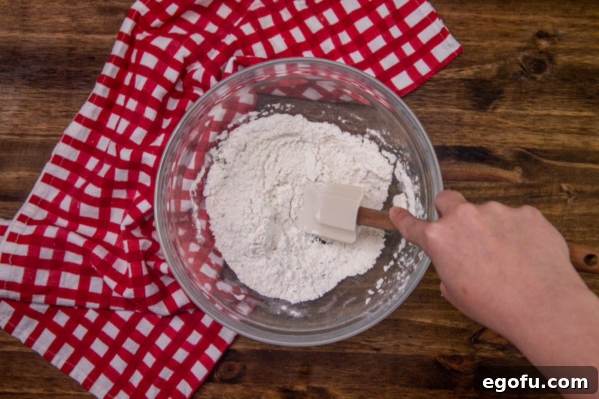 Cheesy Pepperoni Poppers 5 flour, baking powder, Italian seasoning in a white bowl with a spoon.
