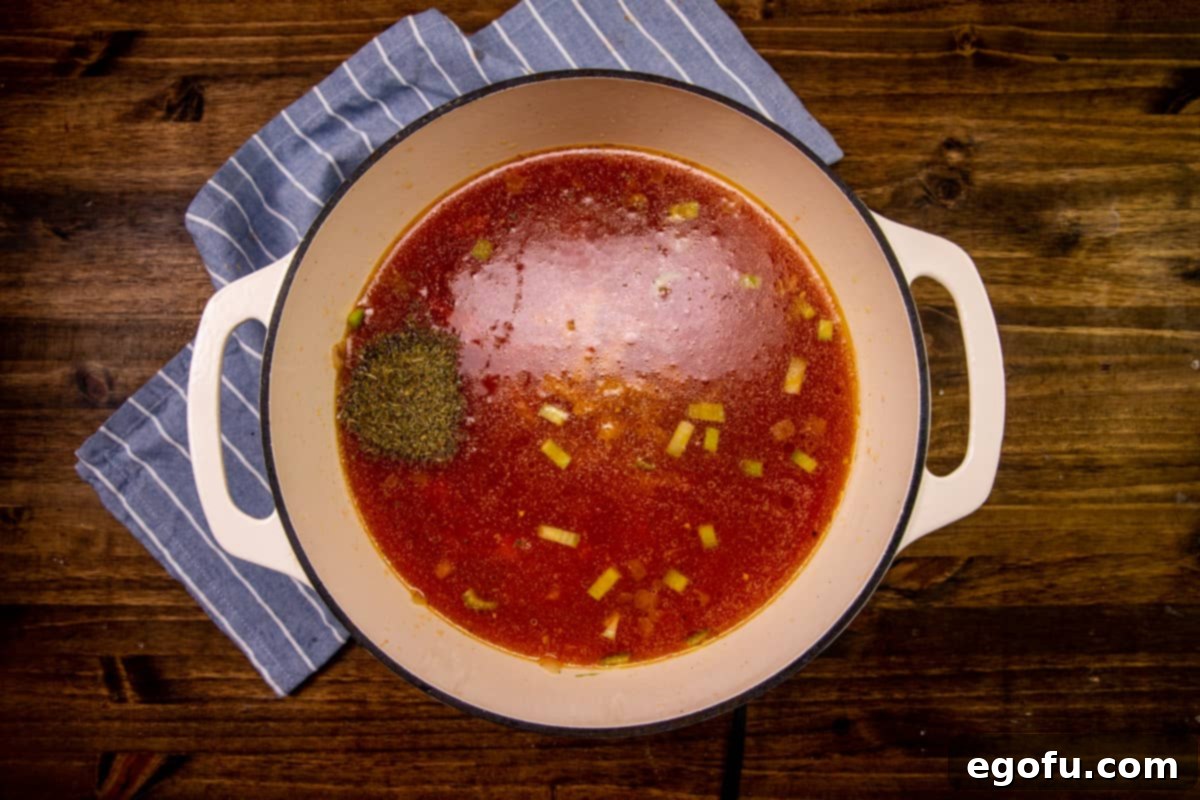 Vegetable broth, Italian seasoning, and crushed tomatoes added to a stock pot