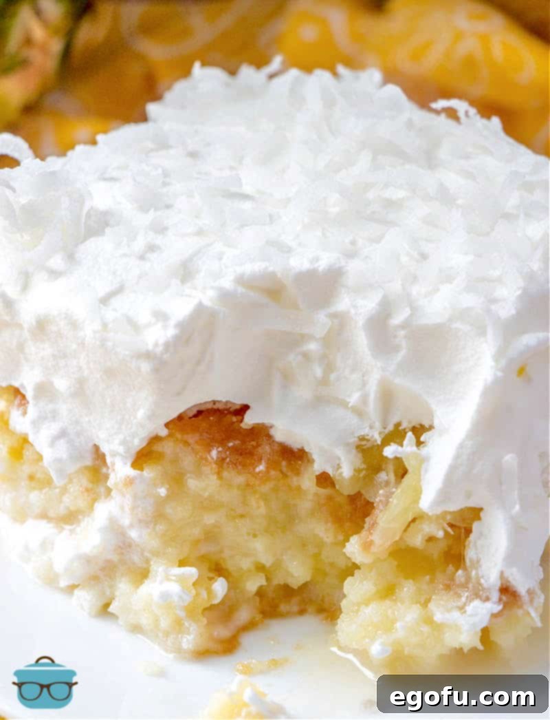 Piña Colada Paradise Poke Cake 12 Close up side photo of a slice of pina colada cake with a bite removed, emphasizing the fluffy texture and tropical layers.