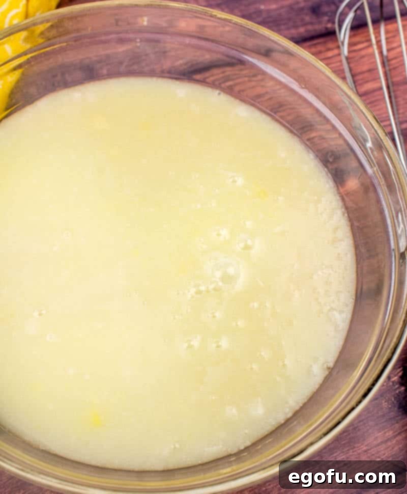 Piña Colada Paradise Poke Cake 7 Pineapple juice mixed with sweetened condensed milk and cream of coconut in a bowl, forming a thin, creamy glaze.