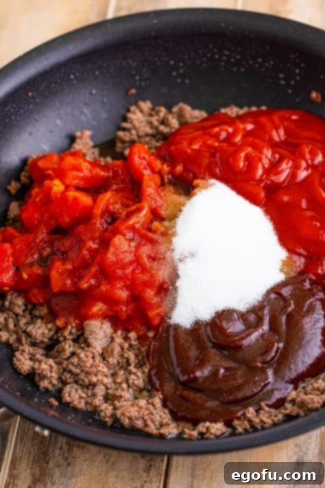 Ground beef, tomatoes, ketchup, bbq sauce, and sugar in a skillet.