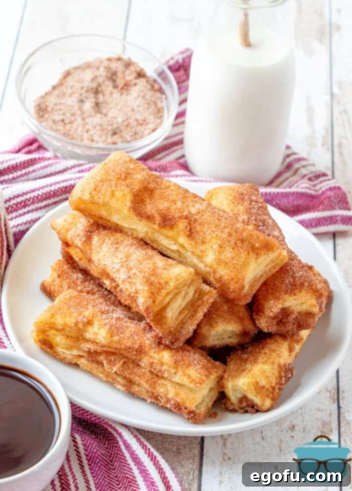 Crispy, golden puff pastry churros coated in cinnamon sugar, artfully arranged on a white plate with a refreshing glass of milk in the background, inviting a delightful dessert experience.