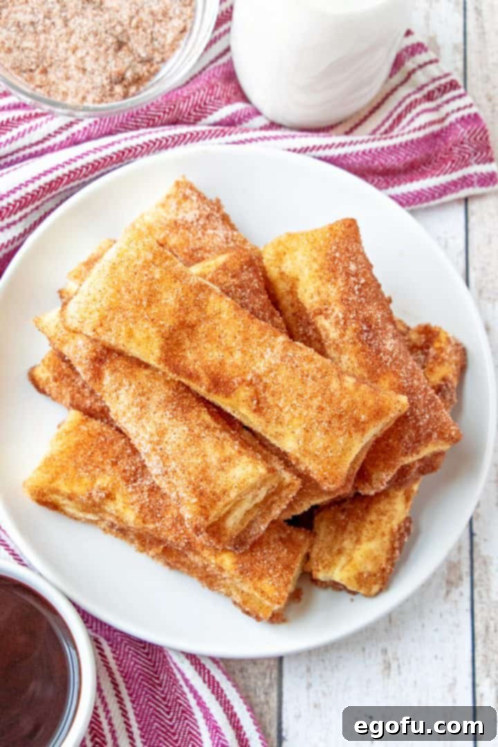 A tempting stack of golden-baked churros, generously coated in aromatic cinnamon sugar, arranged on a pristine white plate, ready to be enjoyed as a delightful dessert.