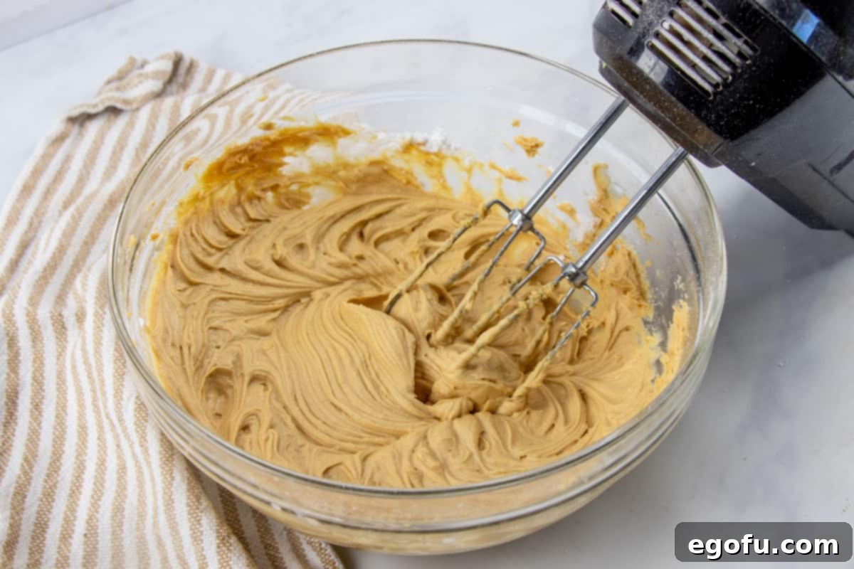 milk and vanilla extract stirred together with peanut butter, margarine and powdered sugar in a large glass bowl.