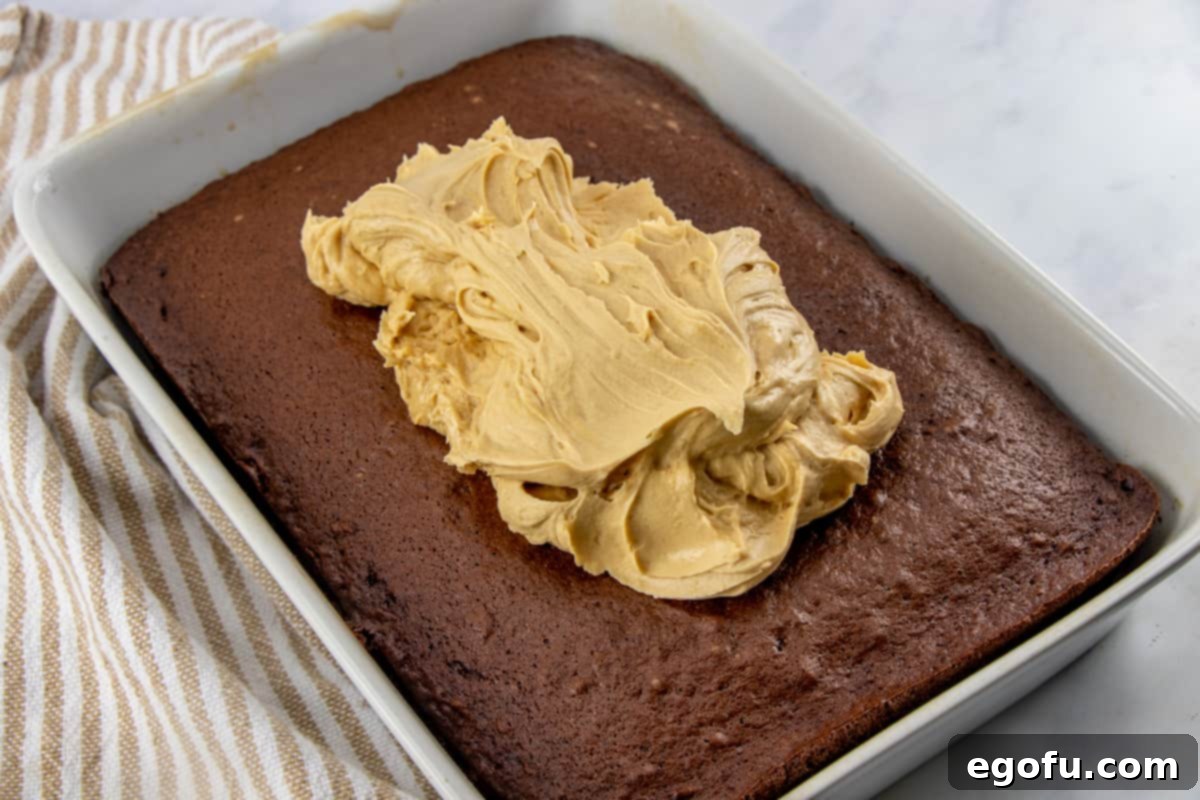 gently spreading peanut butter frosting on cooled chocolate cake.
