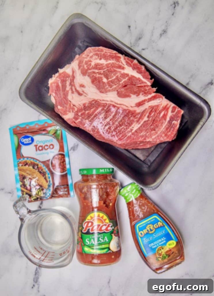 Fiesta-Ready Slow Cooker Shredded Beef 4 Ingredients for Crock Pot Mexican Shredded Beef laid out: a raw chuck roast, a packet of taco seasoning, a jar of salsa, a measuring cup of water, and a bottle of taco sauce, ready for preparation.