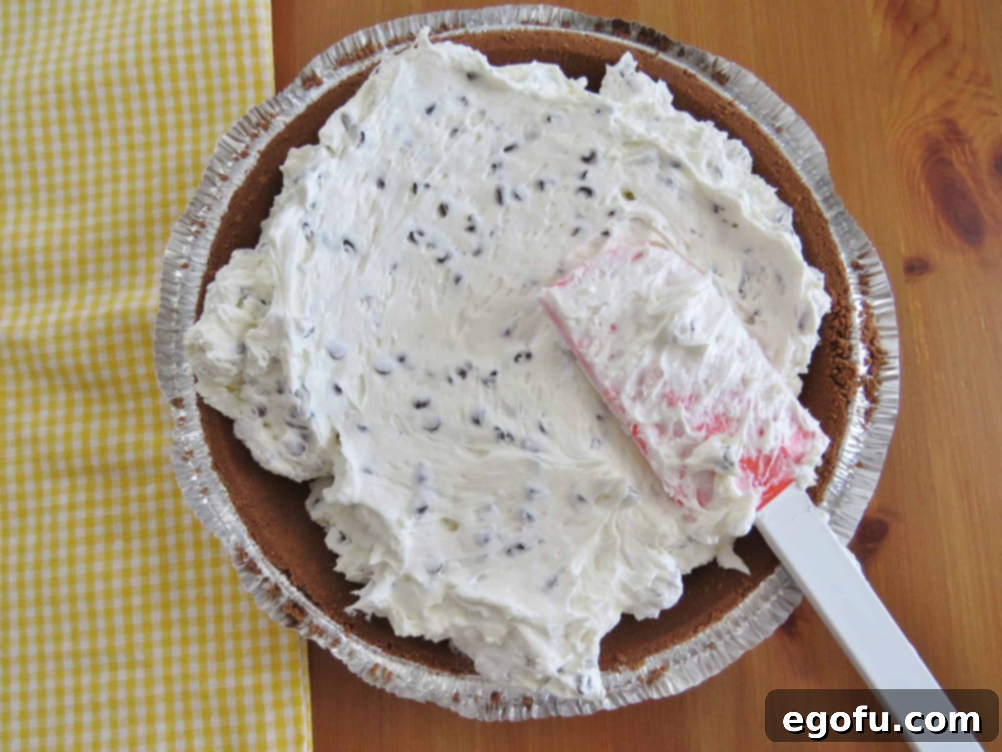 spreading chocolate chip cheesecake mixture into chocolate pie crust.